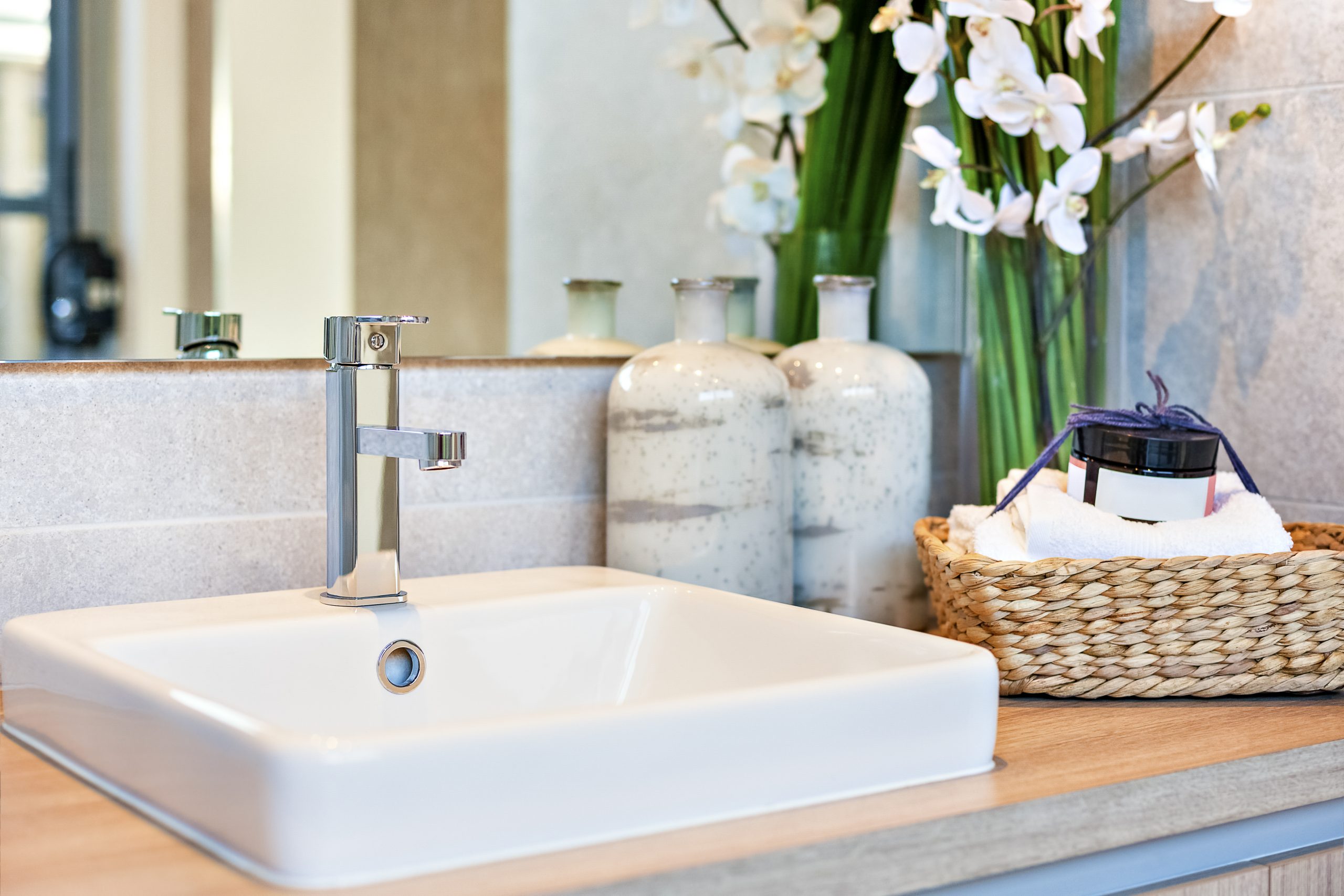 Silver,Taps,And,Ceramic,Sink,Near,Perfume,Bottles,With,Towels