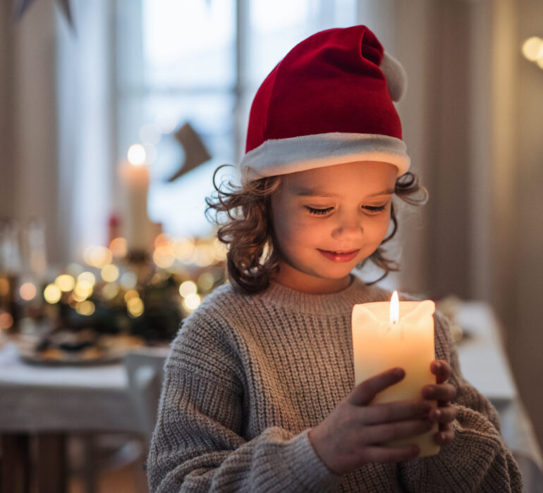 Happy,Small,Girl,Standing,Indoors,At,Christmas,,Holding,Candle.