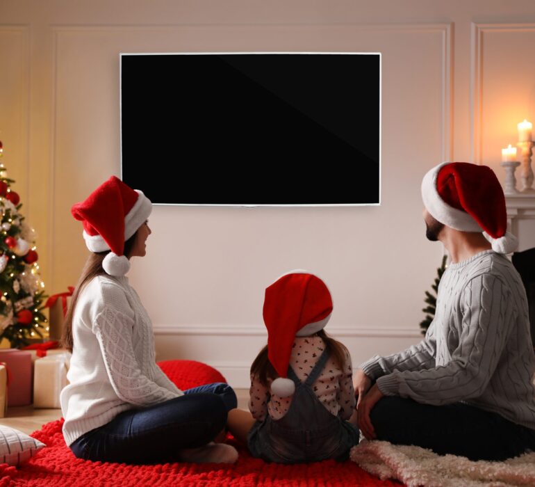 Family,Watching,Tv,In,Room,Decorated,For,Christmas